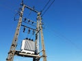 Power line post against a blue sky with a trace from a jet aircraft. Concrete construction with metal wires. Transmission of elect