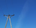 Power line post against a blue sky with a trace from a jet aircraft. Concrete construction with metal wires. Transmission of elect