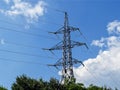Power pylon and high-voltage wires with glass fuses against a bright blue sky with white clouds on a sunny day. Power industry and Royalty Free Stock Photo
