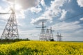 Power line pylons in a blooming rapeseed field with a beautiful sky. transmission and consumption of electricity Royalty Free Stock Photo