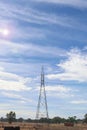 Power line support tower in a blue cloudy sky with lens flare