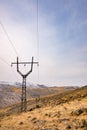 A power line tower is on a hillside with a clear blue sky Royalty Free Stock Photo