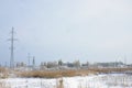 The power line tower is located in a marshy area, covered with snow. Large field of yellow bulrushes