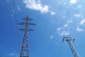 Power line towers against the background of white clouds and a sunny sky, view from below Royalty Free Stock Photo