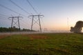 Power line on misty field at sunrise Royalty Free Stock Photo