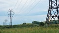 Power line towers, rusted metal beams, summer vegetation and dramatic stormy sky, clouds in background Royalty Free Stock Photo