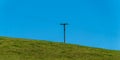 A power lines in a field. Minimalistic landscape, electric post on grass field, sky