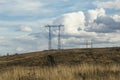 Power lines in the field. Power lines in a spring field against a blue sky and white clouds. Electricity and electrification Royalty Free Stock Photo