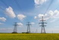 Power lines and high-voltage lines against the backdrop of blooming oilseed rape on a summer day Royalty Free Stock Photo