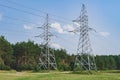 Power lines and high voltage towers. Against the background of a field, forest, grass and blue sky Royalty Free Stock Photo