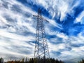 Power lines on a hill, hill or in the mountains against a blue sky with white clouds. Electric lines, towers, wires in Royalty Free Stock Photo