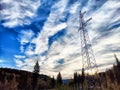 Power lines on a hill, hill or in the mountains against a blue sky with white clouds. Electric lines, towers, wires in Royalty Free Stock Photo