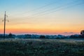 Power lines in misty sunrise over firld