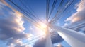 Power lines stretching across a bright sky, with clouds illuminated by sunlight, creating a dynamic perspective of Royalty Free Stock Photo