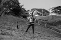 Power Man using scythe. Farmer with a scythe on green grass field. Guy cut grass. Rural farmer on summer meadow mowing Royalty Free Stock Photo