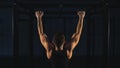 Power muscular bodybuilder guy doing pullups in gym. Fitness man pumping up lats muscles.