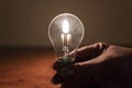 Power outage concept. Light bulb in hand by the light of a burning candle Royalty Free Stock Photo