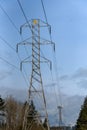 Power pilons and power lines on a sunny blue sky day, tower in the background with wireless antennas