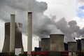 power plant with chimneys and steaming cooling towers, gray clouds rise in the sky Royalty Free Stock Photo