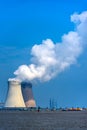 Power plant cooling towers emit white steam clouds in the clear blue sky Royalty Free Stock Photo