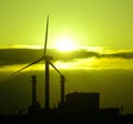 Power plant and wind turbines backlit at sunrise Royalty Free Stock Photo