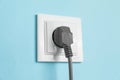 Power socket with inserted plug on light blue wall, closeup. Electrical supply Royalty Free Stock Photo