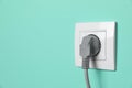 Power socket with inserted plug on turquoise wall, space for text. Electrical supply Royalty Free Stock Photo