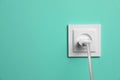 Power socket with inserted plug on turquoise wall, space for text. Electrical supply Royalty Free Stock Photo