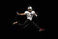Portrait young American football player, athlete in black white sports uniform training isolated on dark studio Royalty Free Stock Photo