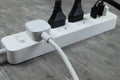 Power strip with multiple electrical cords plugged in on gray background