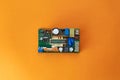 Power supply Board on orange background, top view. Printed circuit board PCB