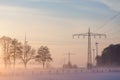 Power supply lines poles and wind genertor in the fog Royalty Free Stock Photo