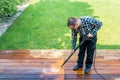 power washing - man cleaning terrace with a power washer - high water pressure cleaner on wooden terrace surface Royalty Free Stock Photo