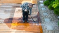 power washing - man cleaning terrace with a power washer - high water pressure cleaner on wooden terrace surface Royalty Free Stock Photo