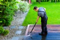 Power washing - man cleaning terrace with a power washer - high water pressure cleaner on wooden terrace surface Royalty Free Stock Photo