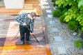 Power washing - man cleaning terrace with a power washer - high water pressure cleaner on terrace surface