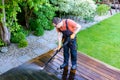 Power washing - man cleaning terrace with a power washer - high water pressure cleaner on wooden terrace surface Royalty Free Stock Photo