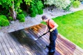 Power washing - man cleaning terrace with a power washer - high water pressure cleaner on wooden terrace surface Royalty Free Stock Photo
