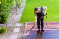 power washing - man cleaning terrace with a power washer - high water pressure cleaner on wooden terrace surface Royalty Free Stock Photo