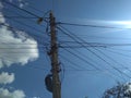 Power wires on a pillar against a blue sky