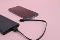 Powerbank charging a smartphone. Mobile phone or smartphone battery charging from portable powerbank with white usb cable. Grey Royalty Free Stock Photo