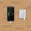 Powerbank charging smartphone on wooden desk