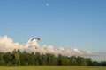 Powered paraglider flying against blue sky with clouds and moon Royalty Free Stock Photo