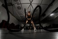 Powerful attractive muscular woman doing battle workout with ropes at functional gym Royalty Free Stock Photo