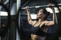 Powerful attractive woman CrossFit trainer do pull ups during workout