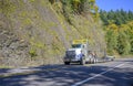 Powerful big rig semi truck with oversize load sign on the roof transporting oversized cargo on step down semi trailer driving Royalty Free Stock Photo