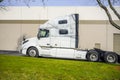 Powerful big rig semi truck tractor with rest compartment for truck drivers standing on the warehouse parking lot waiting for Royalty Free Stock Photo