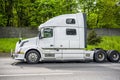 Powerful big rig semi truck tractor running on the road with fence and trees on the side to warehouse for pick up the loaded semi Royalty Free Stock Photo