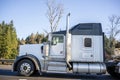 Powerful big rig white classic American semi truck with black roof and semi trailer running on the road Royalty Free Stock Photo