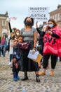 A powerful black female leader wears a Black Lives Matter PPE face mask and hugs her Superhero son at a BLM protest in Richmond,